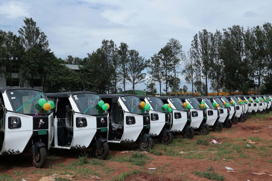 A long row of new EV autos decorated with balloons, ready for handover
