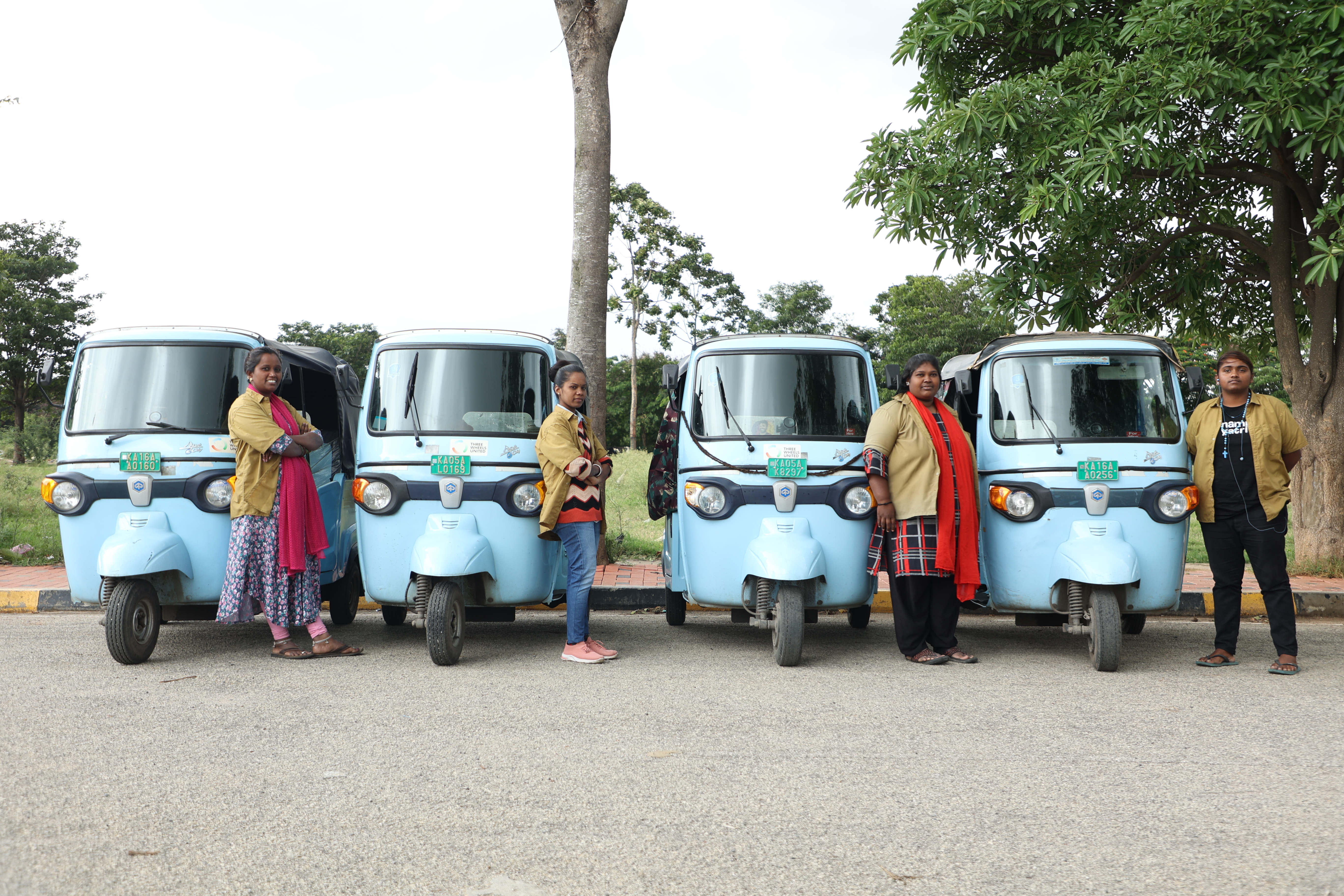 Mahila Shakti drivers standing beside their EV autos