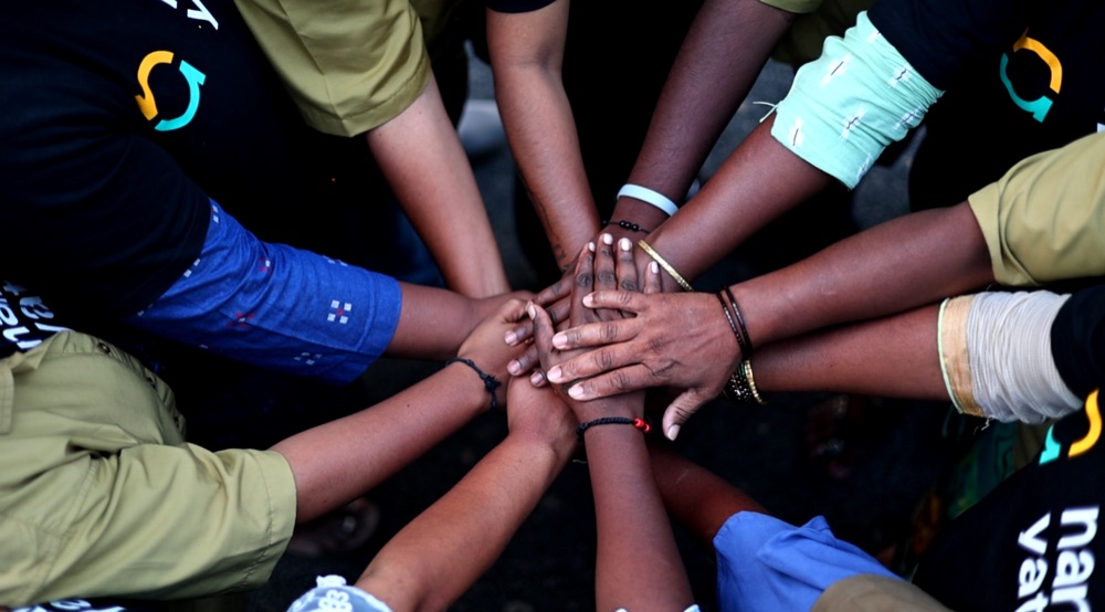 A circle of hands stacked together in solidarity